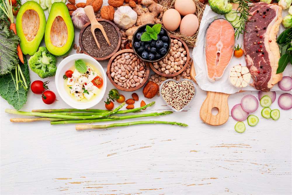 Mesa de superficie branca com vários grãos, frutas, salmão, verduras e hortaliças